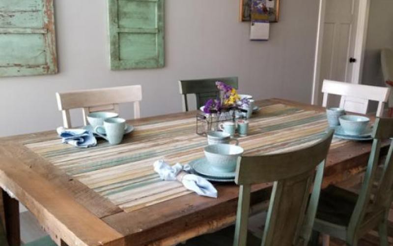 A cozy dining setup with a striped table runner, cups, and a floral centerpiece.