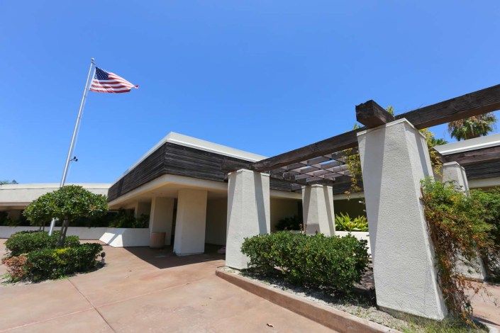A modern building with an American flag flying under a clear blue sky.