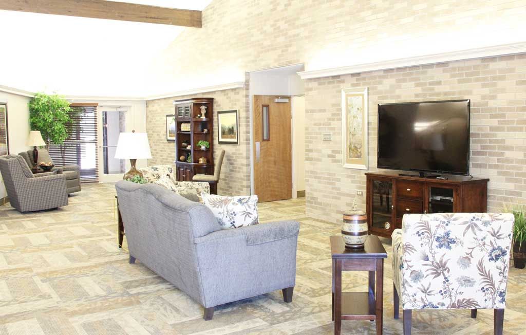 A cozy living room with a sofa, television, and bookshelf against a brick wall.