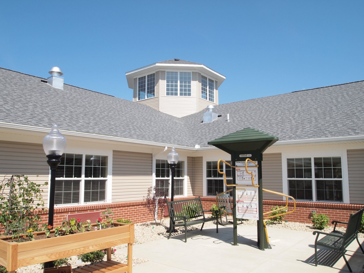 A bright and sunny courtyard featuring outdoor seating and a modern building with large windows.