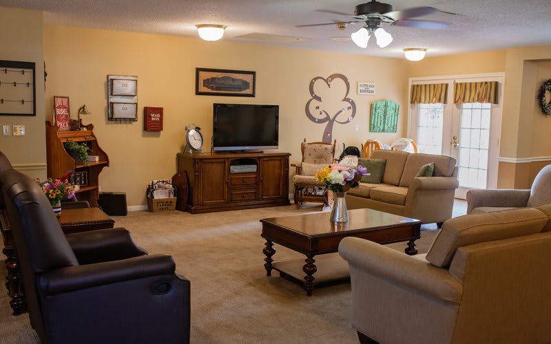 A cozy living room with sofas, a television, and a coffee table adorned with flowers.