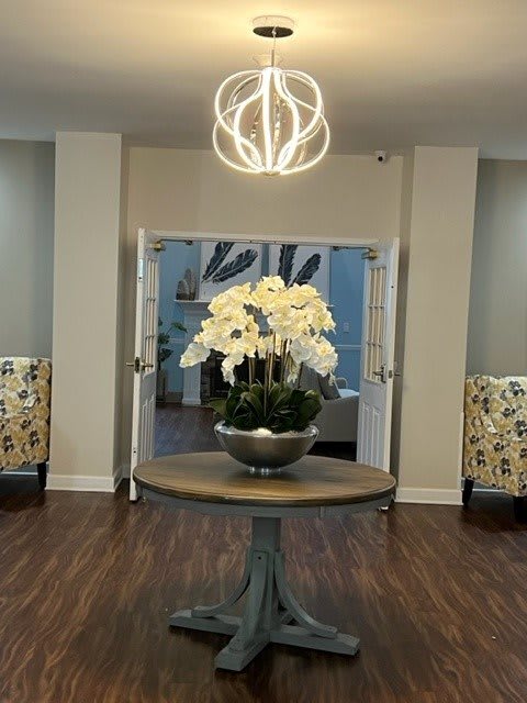 A modern interior featuring a round table with a floral arrangement and a stylish chandelier.