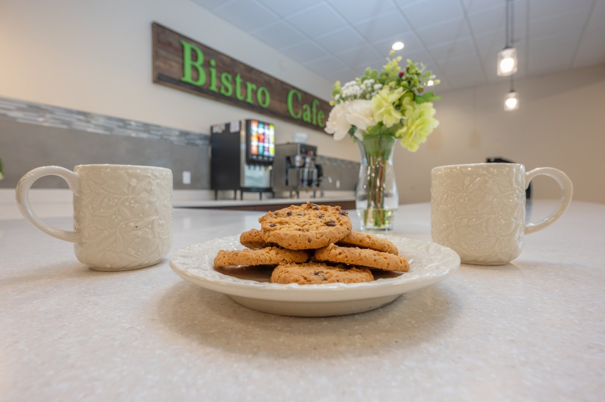 A cozy bistro setting with a plate of cookies and coffee mugs on the table.