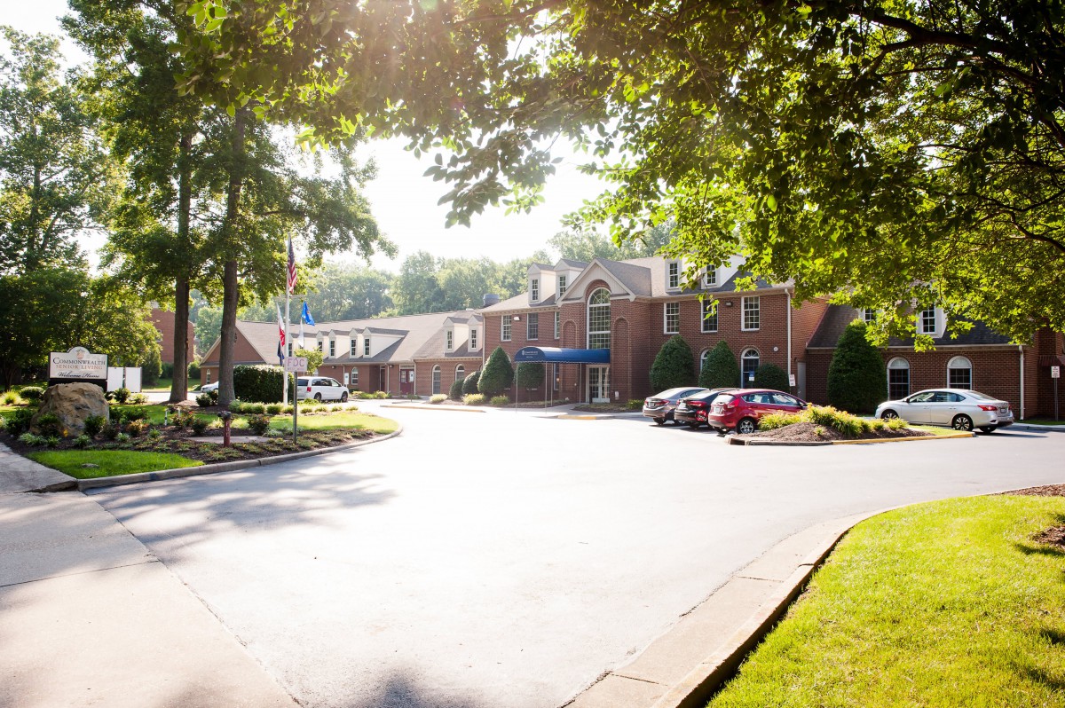 A suburban residential building with a parking lot, under the warm glow of sunlight filtered through trees.