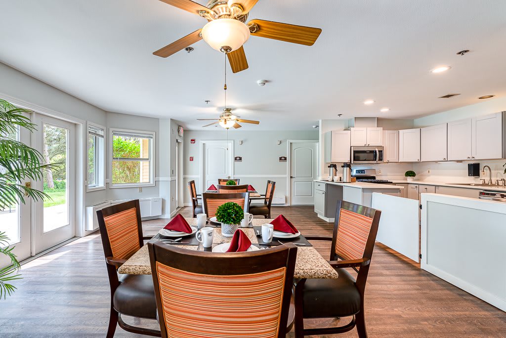 A modern dining room with a table set for four, connected to an open kitchen area.