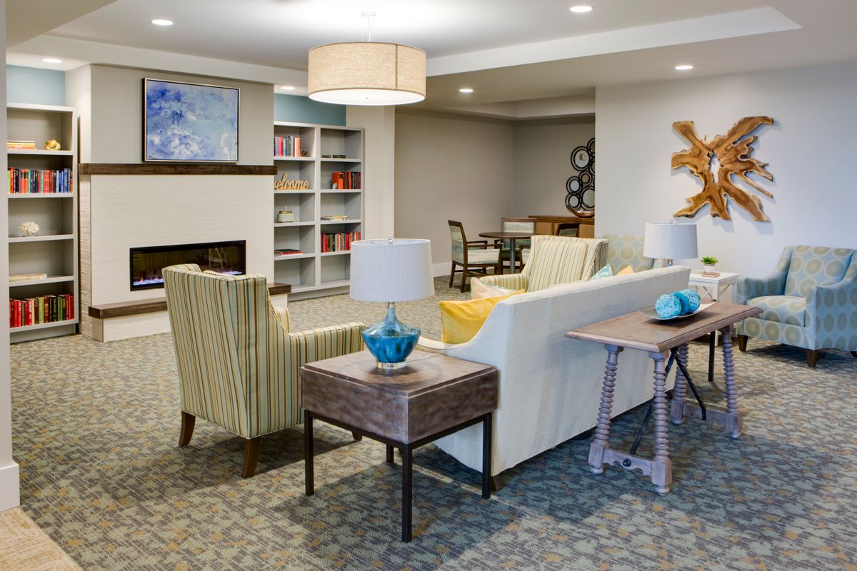 A modern living room area featuring comfortable seating, stylish lighting, and bookshelves.