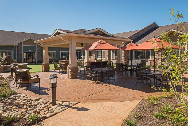 A spacious outdoor patio area featuring tables with umbrellas and surrounding buildings.