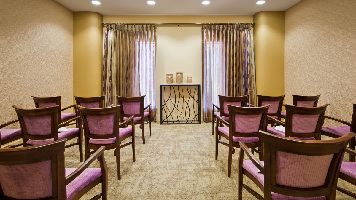 A small, well-lit conference room with arranged chairs and elegant curtains.
