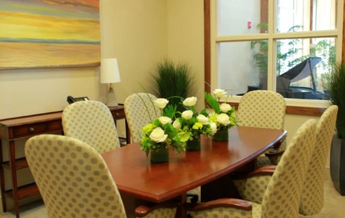 A well-appointed conference room featuring a wooden table, upholstered chairs, and decorative floral arrangements.