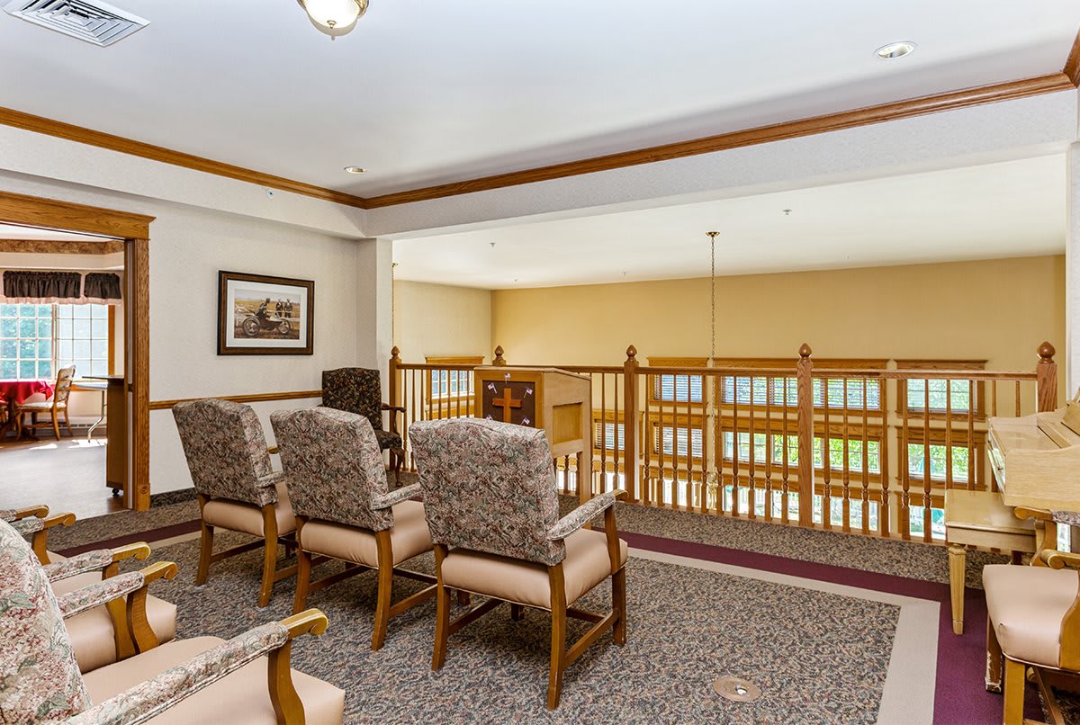 A cozy seating area with upholstered chairs overlooking a railing, featuring warm wood trim and a carpeted floor.