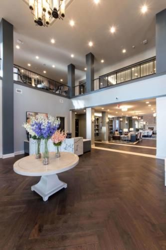 A modern and spacious lobby with elegant interior design, featuring a table adorned with flowers.