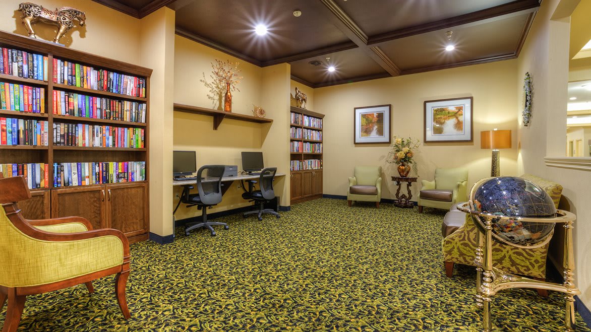 A cozy office space featuring workstations with computers, bookshelves, and comfortable seating.