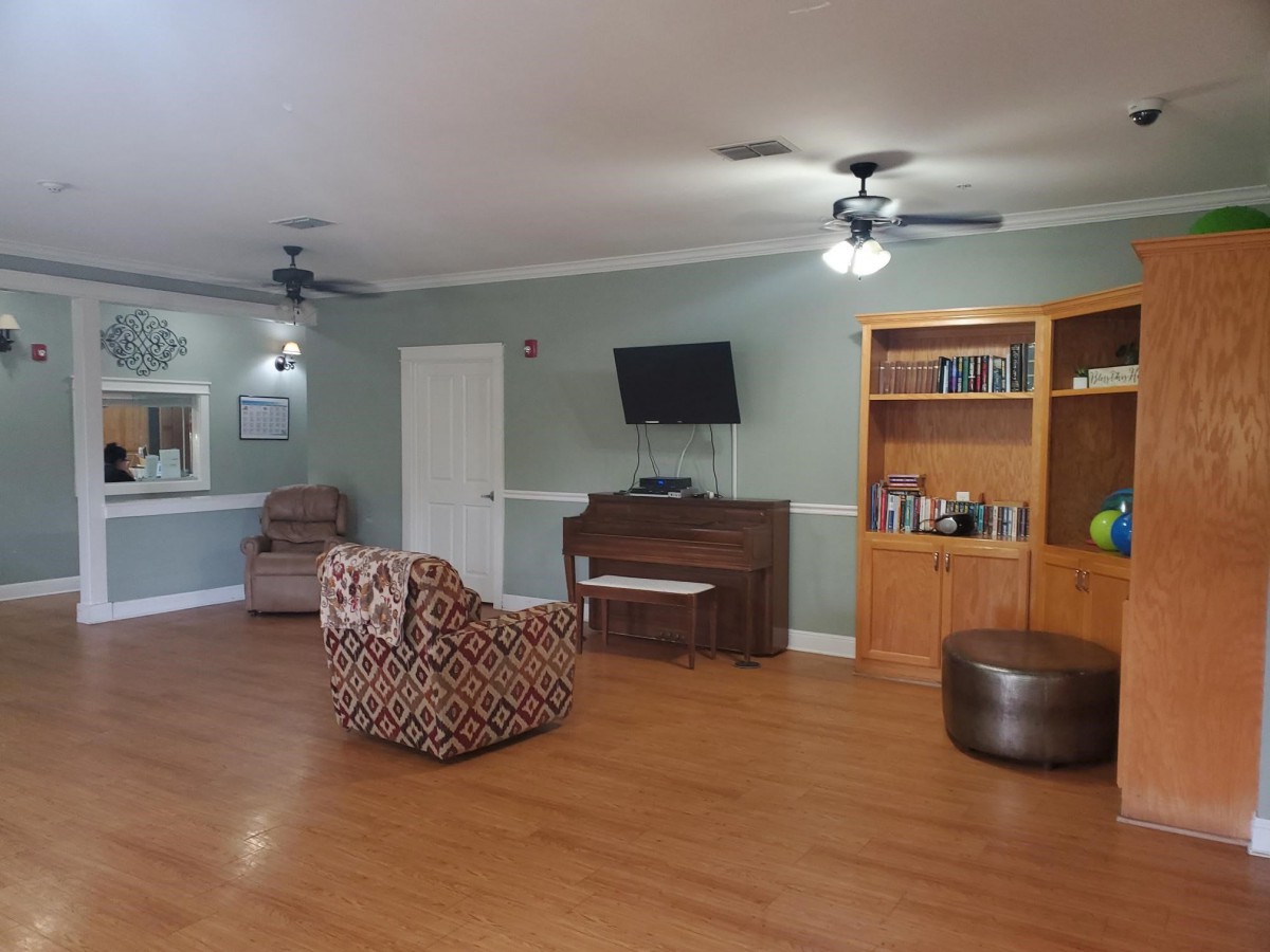 A cozy living room with a piano, bookshelves, and a ceiling fan.