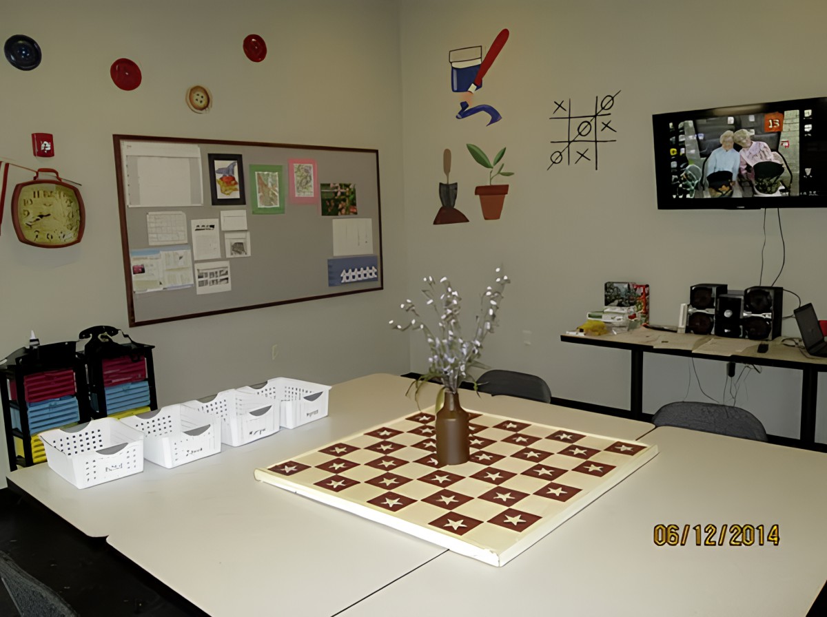 A classroom setup with tables arranged in a square, featuring a chessboard pattern centerpiece and various decorations on the walls.