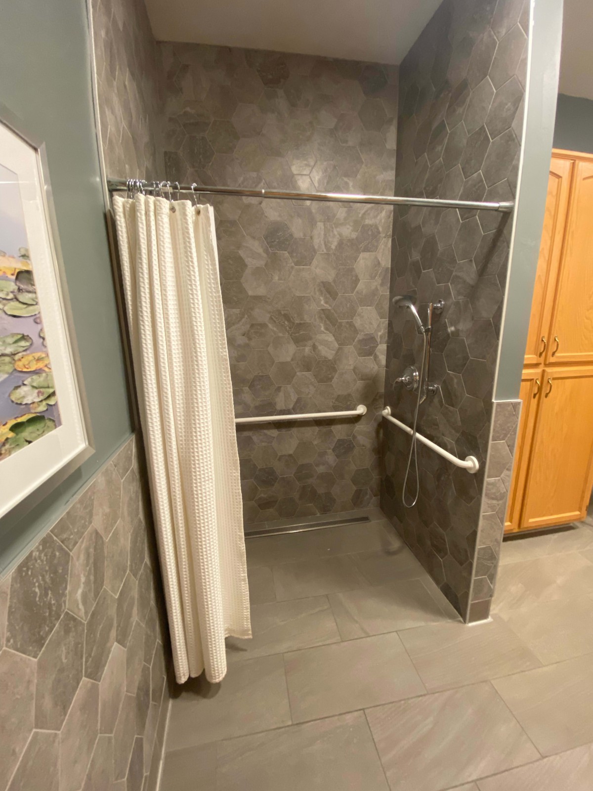 An accessible bathroom shower with grab bars and a curtain.