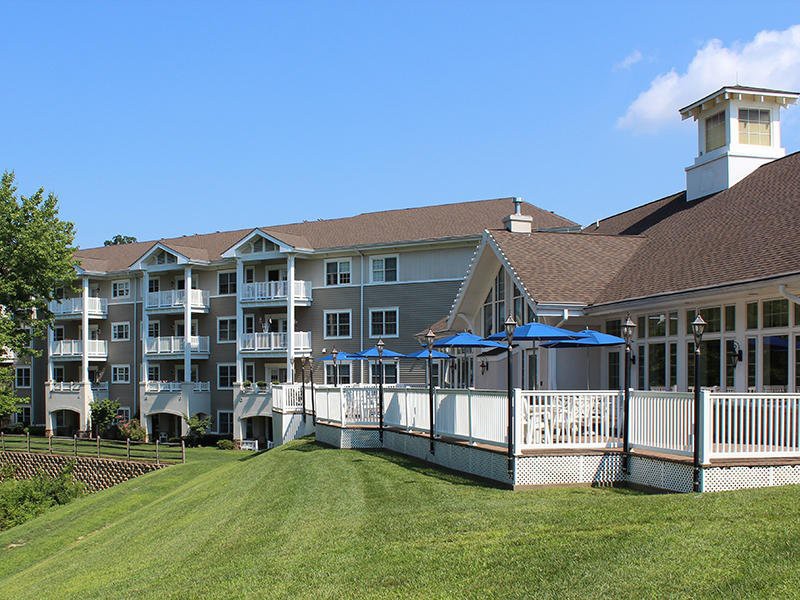 A modern apartment building with balconies and a spacious lawn on a clear day.