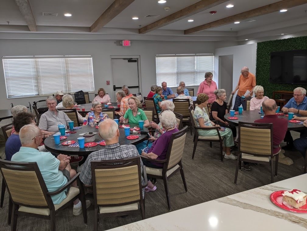 A community gathering with people seated at tables in an indoor setting.