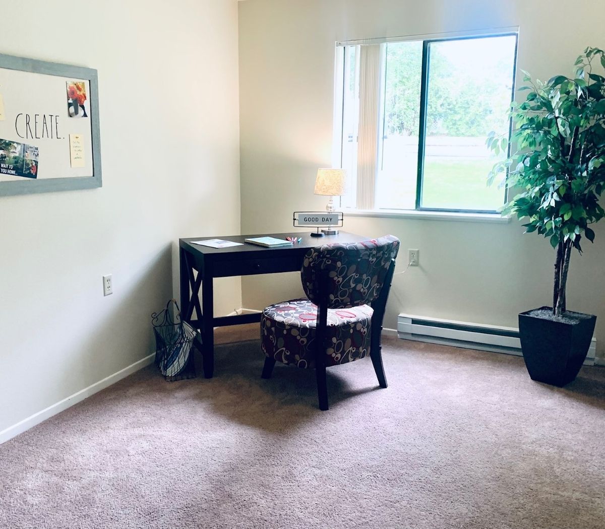 A minimalist study area featuring a desk with a lamp, a chair, and a potted plant by the window.