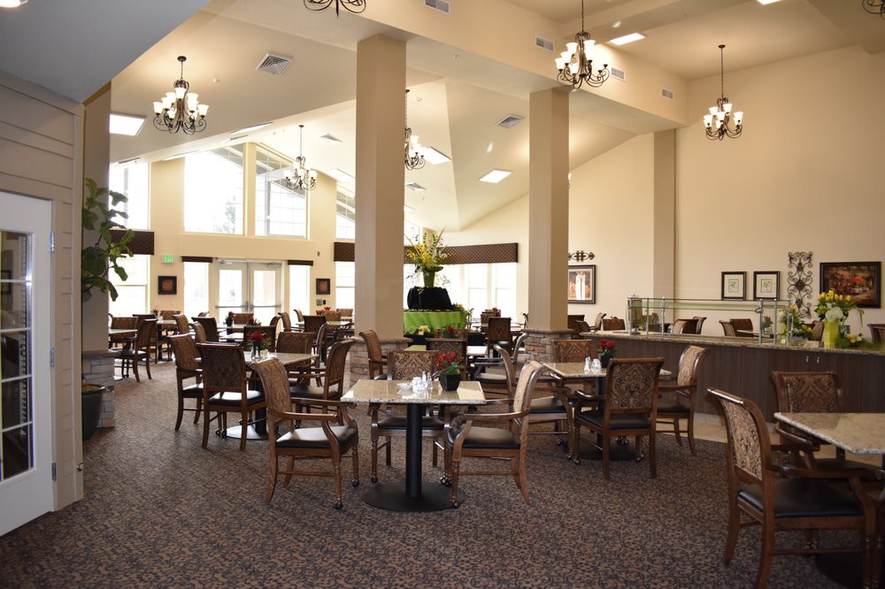 A spacious dining area featuring elegant chandeliers, neatly arranged tables and chairs, creating a welcoming atmosphere.