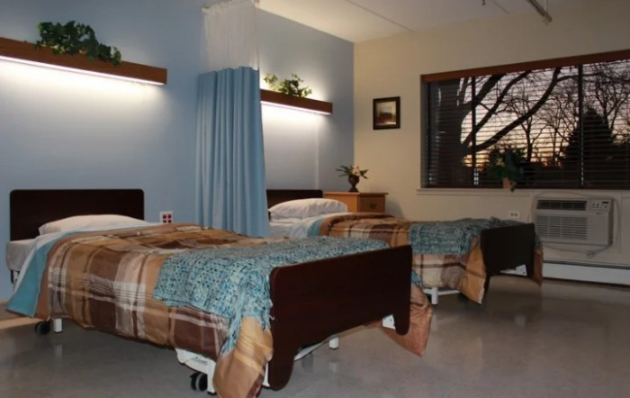 A clean and organized hospital room with two beds separated by a curtain.