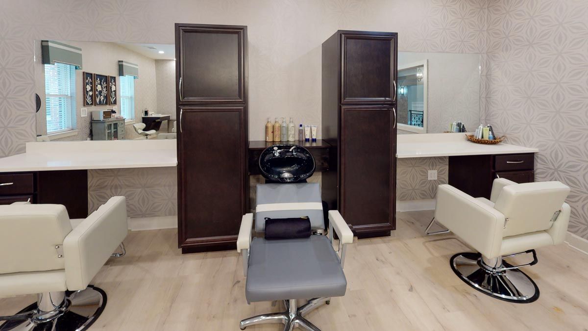 A modern hair salon interior with a styling chair, sink, and mirrors.