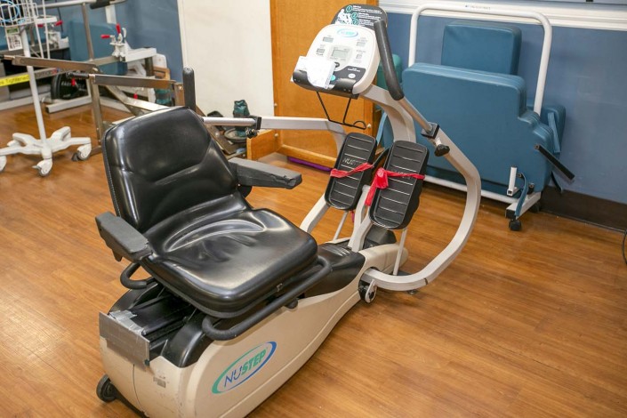 A recumbent exercise bike positioned in a healthcare facility, often used for rehabilitation and fitness purposes.