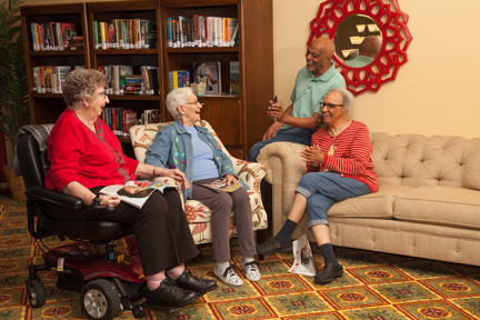 A group of seniors enjoying a conversation in a community library setting.