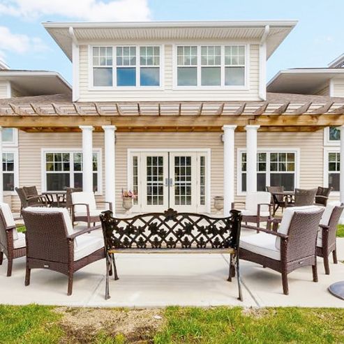 A beautiful patio setup with comfortable chairs and a pergola in a backyard setting.