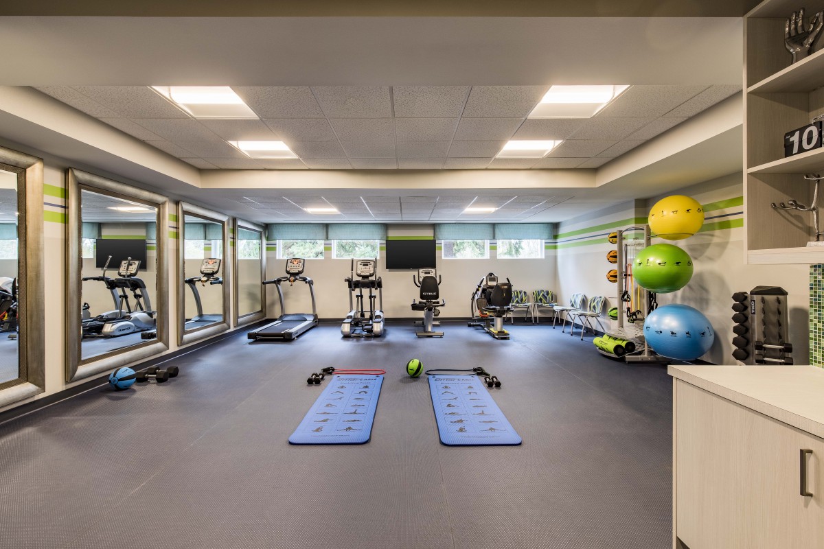 A well-equipped gym with various exercise machines, weights, and yoga mats, designed for fitness and workout sessions.