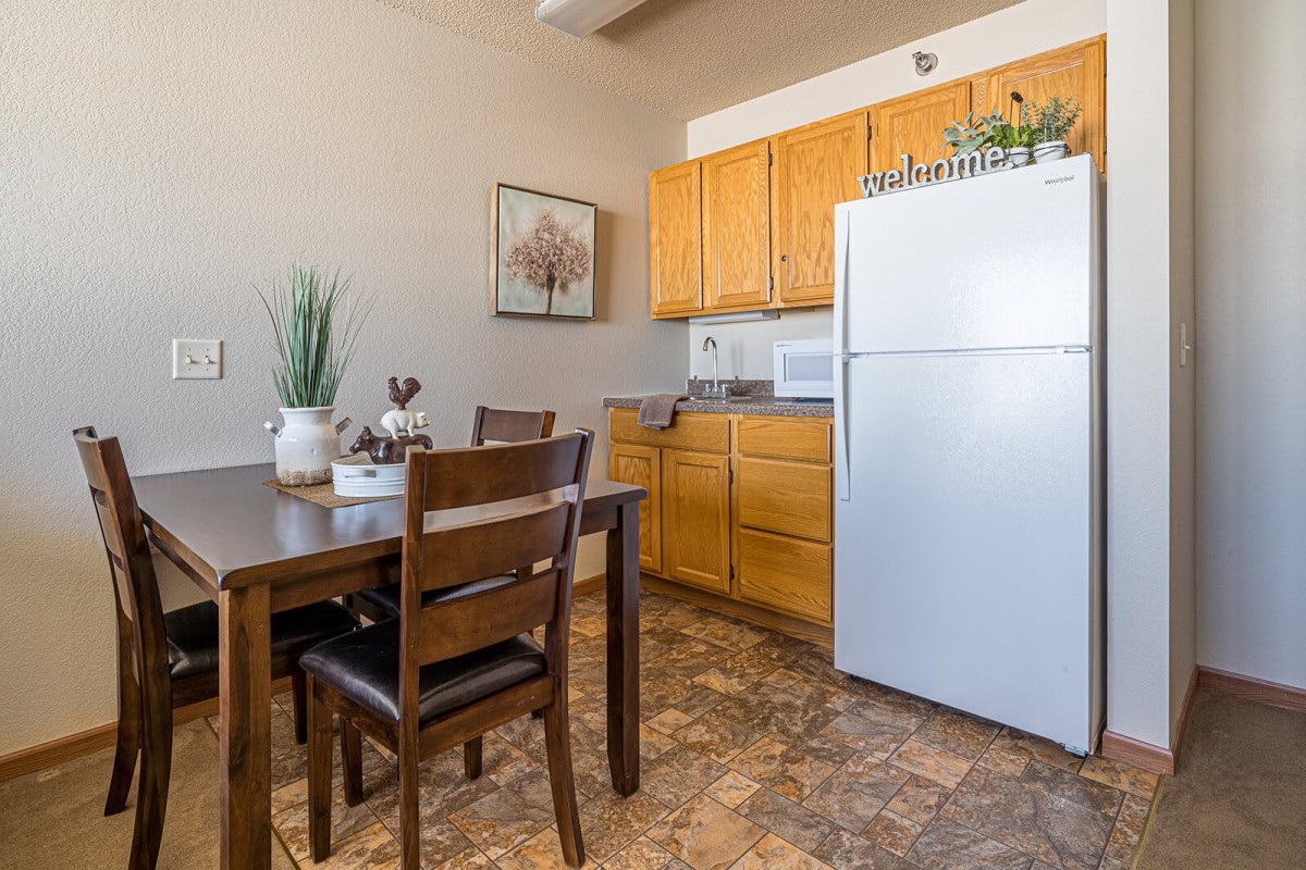 A cozy kitchen and dining area featuring wooden cabinets, a white refrigerator, and a dining table with chairs.