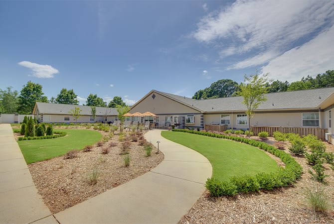 A sunny view of a building with a landscaped garden and pathway.