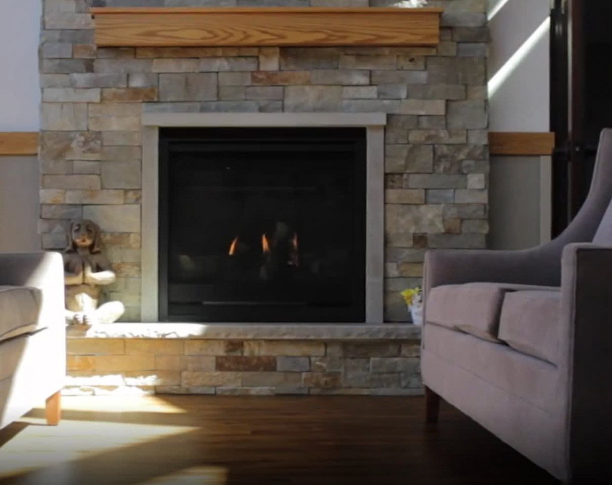 A cozy living room features a stone fireplace with a comfortable couch nearby.