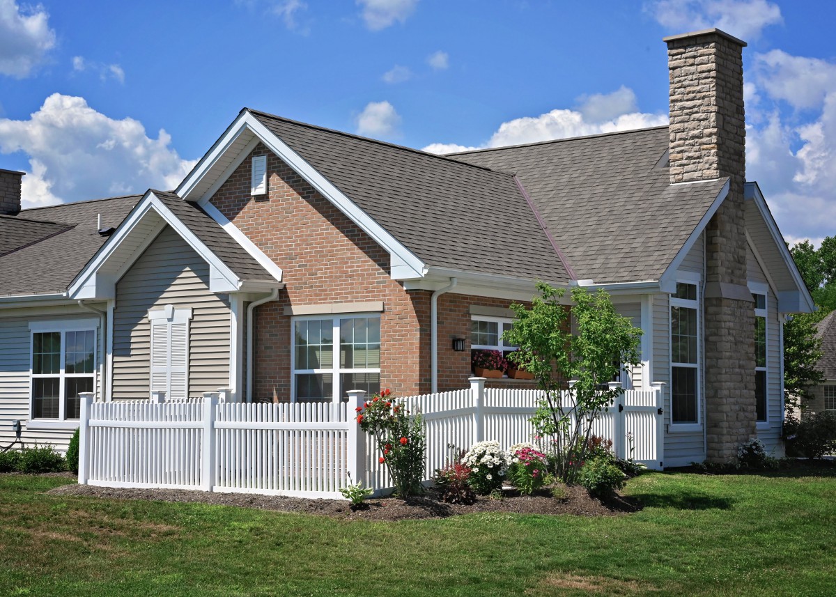 A beautiful single-story house with a white fence and a well-maintained garden.