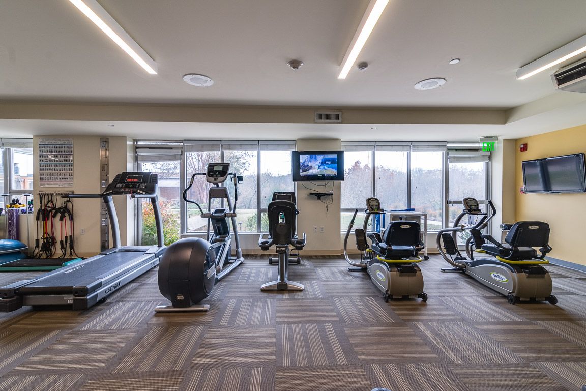 A modern gym equipped with treadmills, stationary bikes, and other cardio machines.