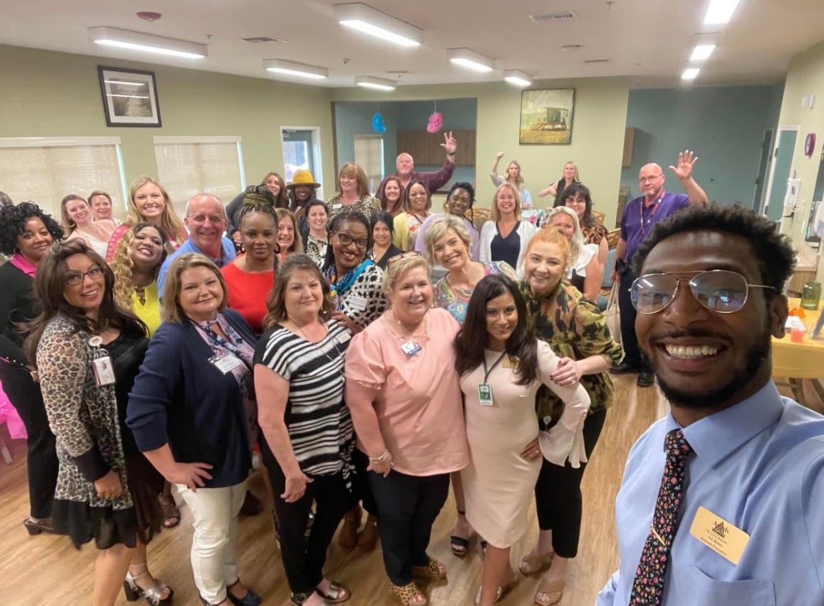A joyful group of people gathered indoors, smiling for a photo.