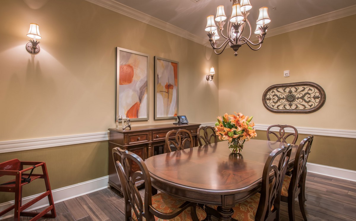 A traditional dining room with a wooden table and chandelier, adorned with floral decor and artwork on the walls.