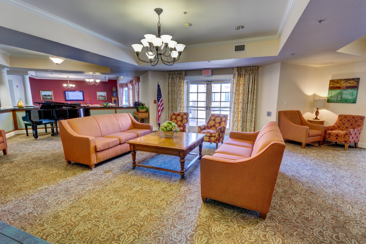 A cozy living room with comfortable sofas and a central coffee table, illuminated by a chandelier.