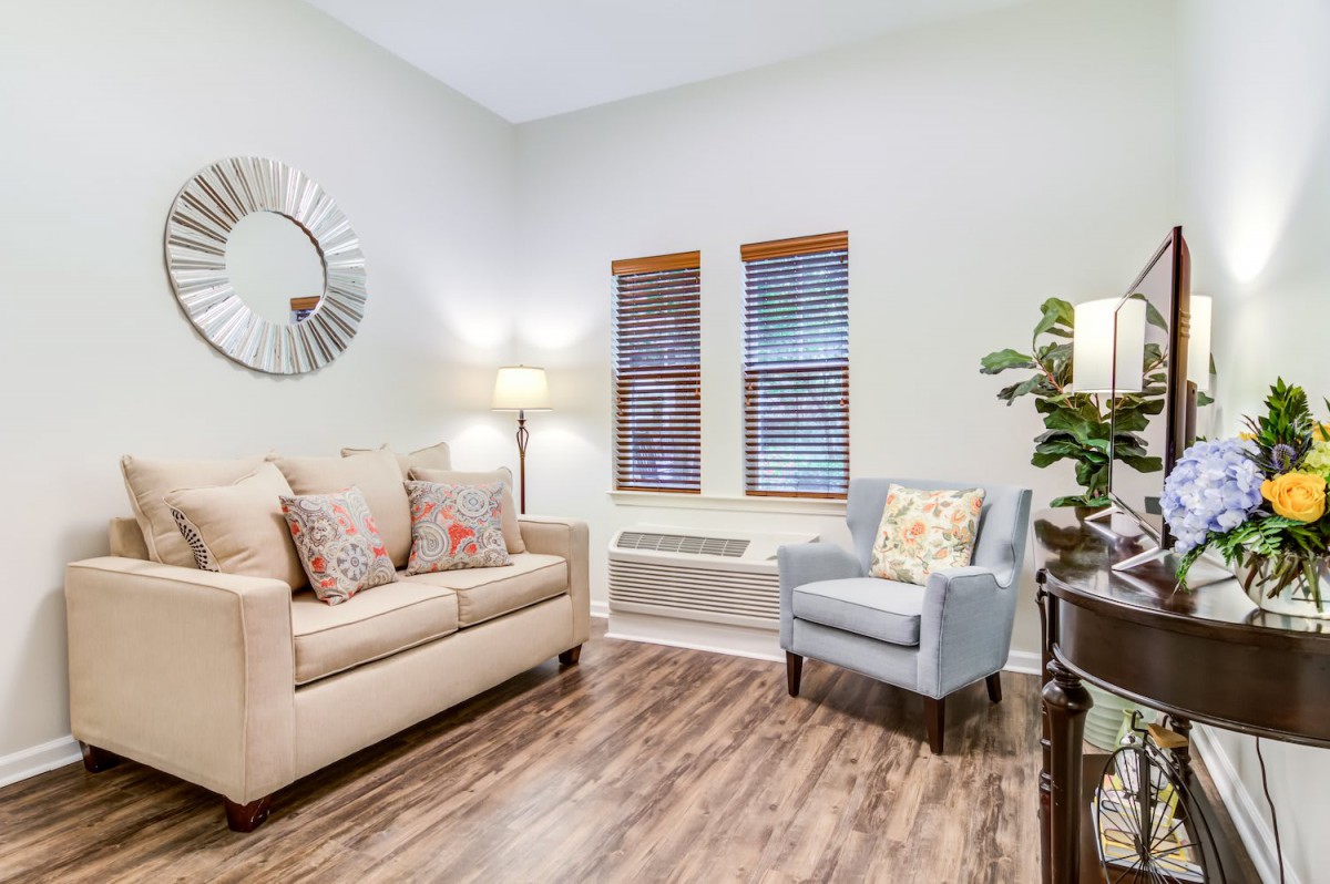 A cozy living room with a sofa, armchair, and wooden flooring.