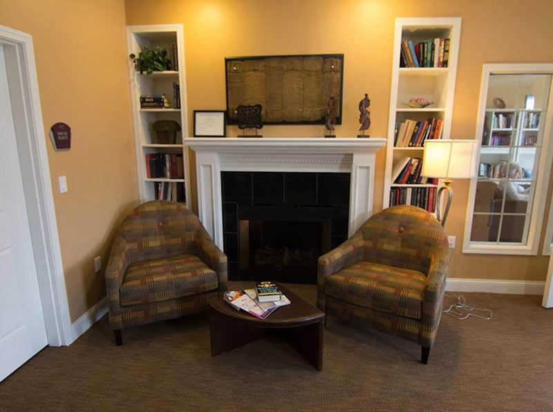 A cozy living room with two armchairs, a fireplace, and bookshelves.