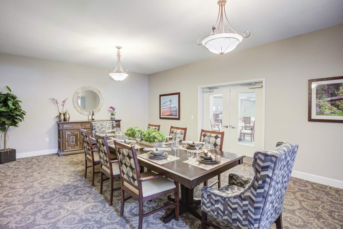 A well-decorated dining room with a large table and elegant chandeliers.