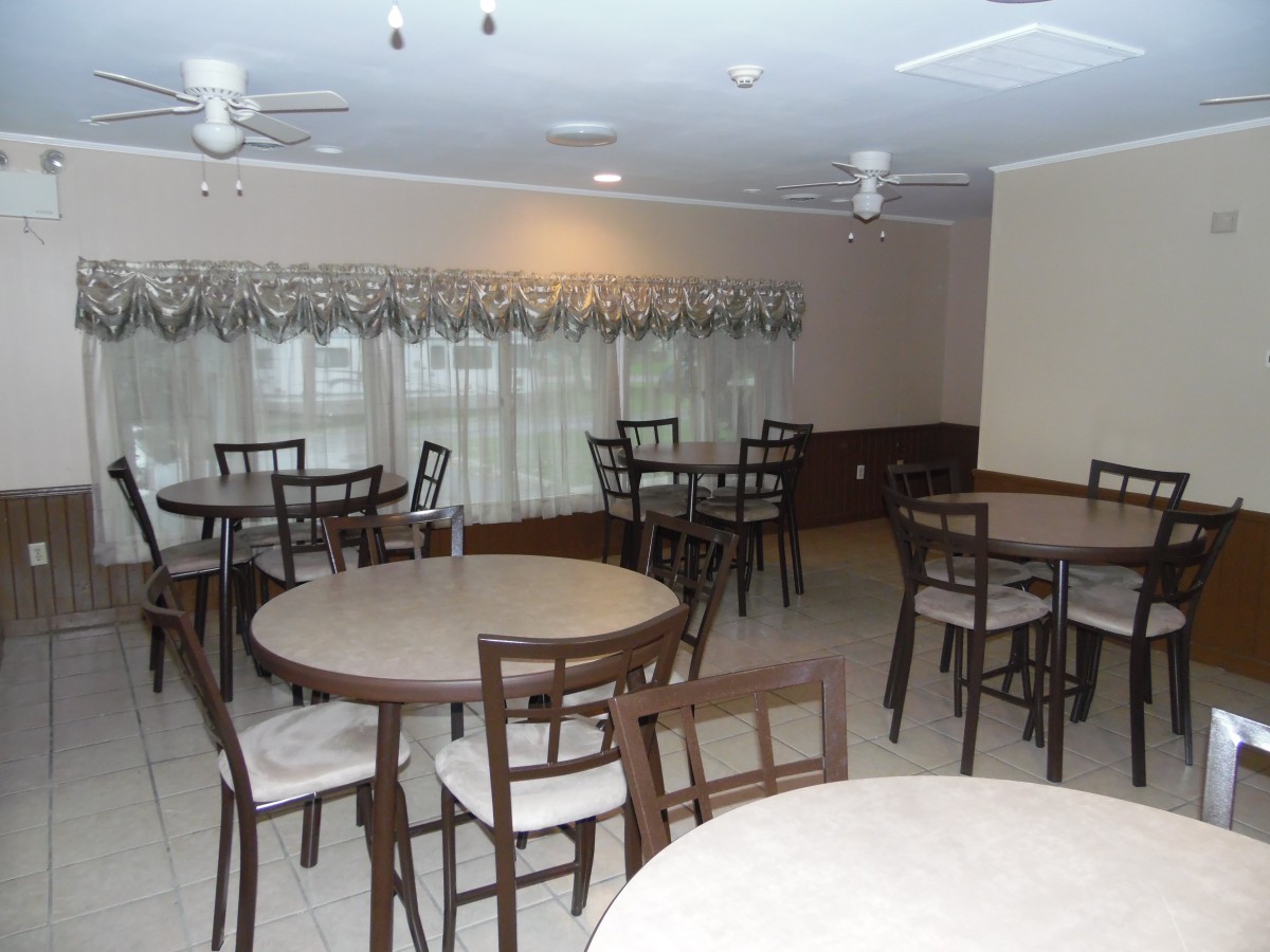 A dining room with multiple round tables and chairs arranged neatly.