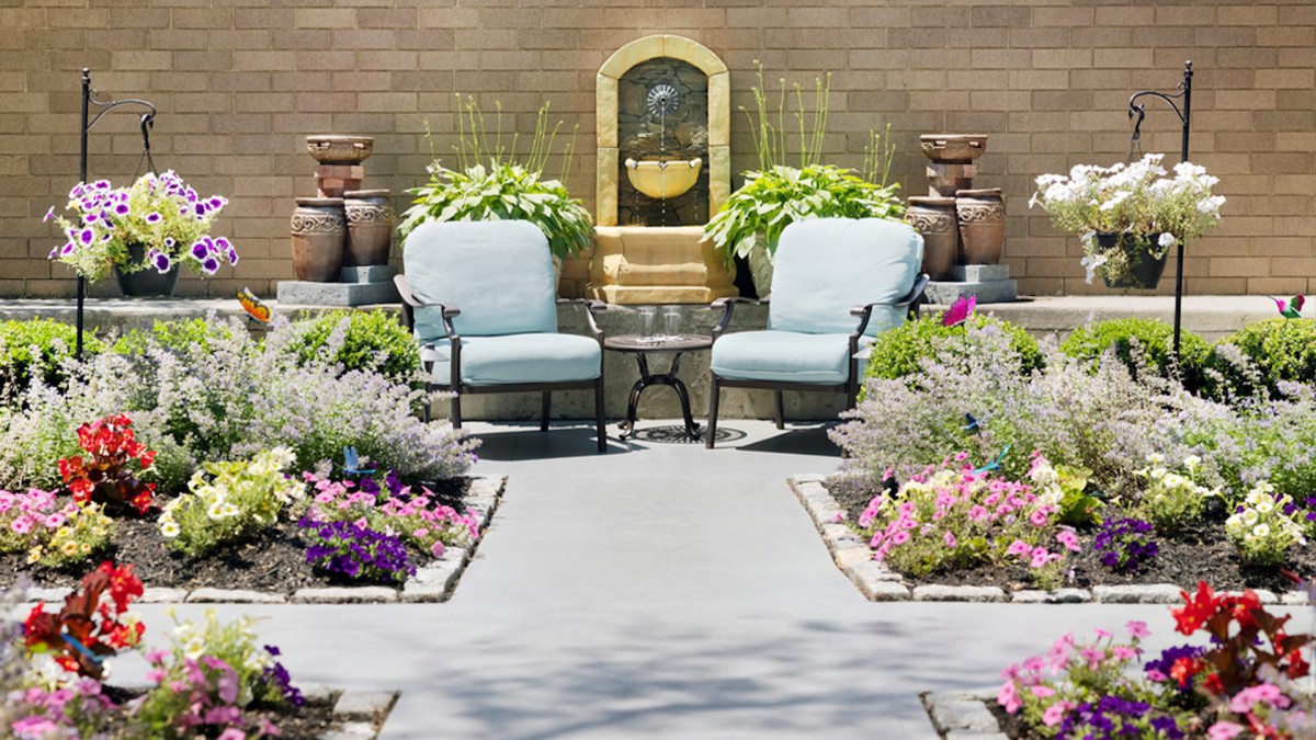 A cozy garden patio with cushioned chairs and vibrant flower arrangements.