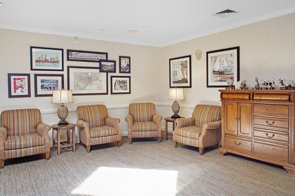 A cozy living room seating area with three striped armchairs, framed artwork on the walls, and table lamps.