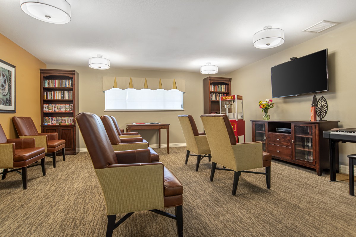 A cozy seating area with several chairs, bookshelves, and a television mounted on the wall.