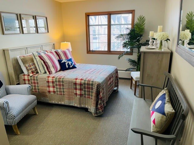 A cozy bedroom with a neatly made bed, colorful pillows, and warm lighting.