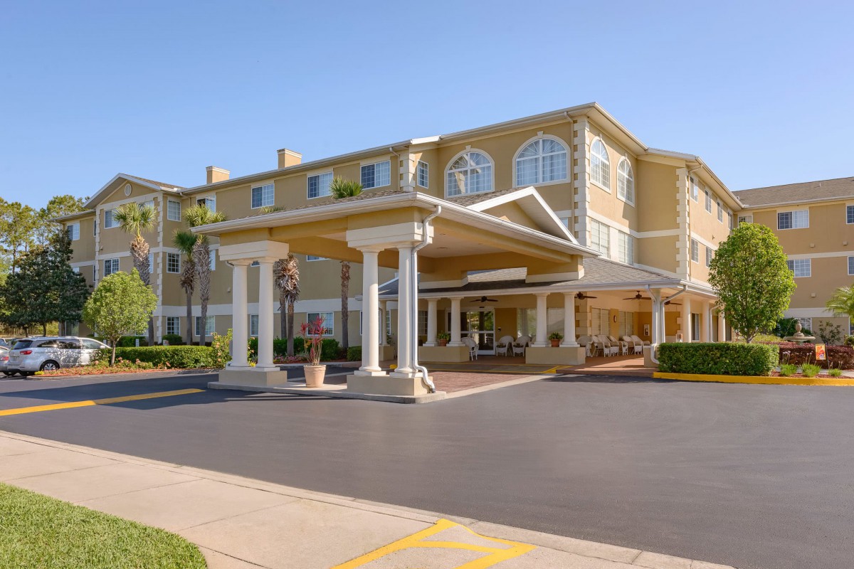 The exterior of a hotel with a covered entrance, set against a clear blue sky.