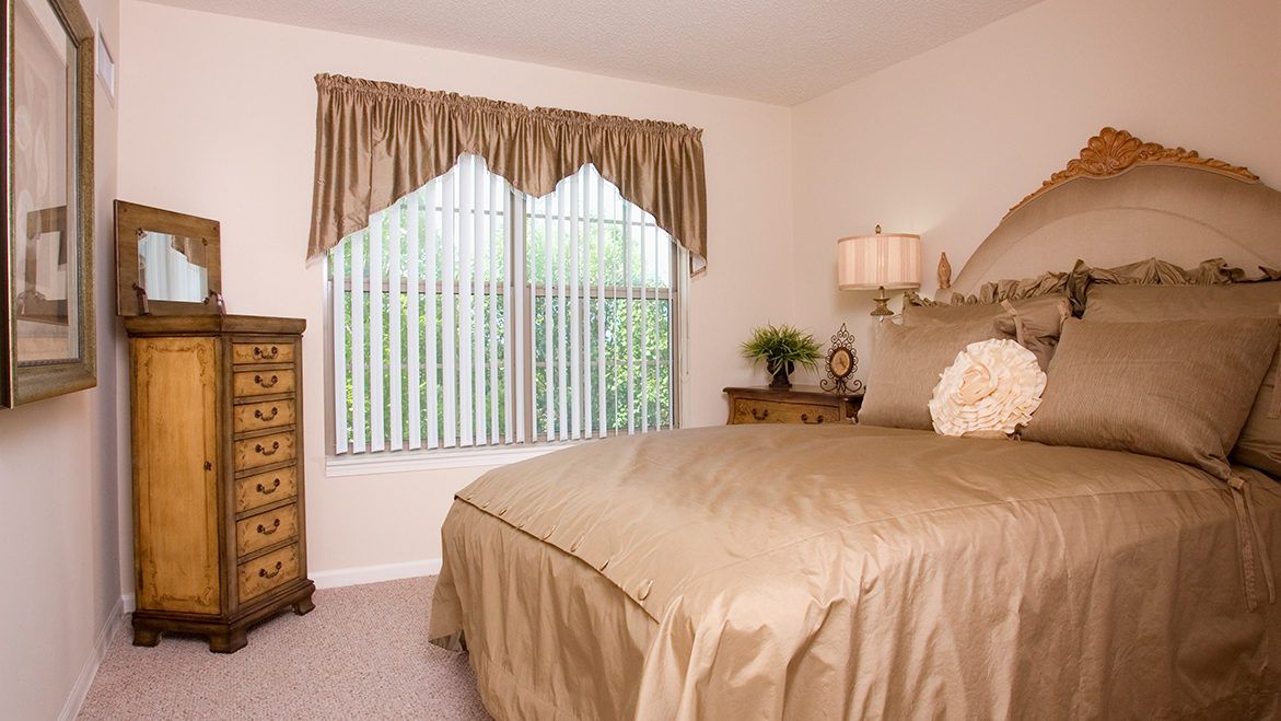 A cozy bedroom with a large bed, wooden furniture, and a window with curtains.