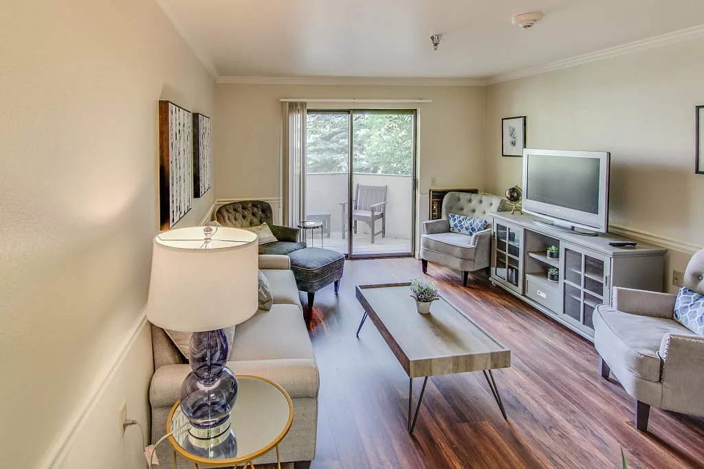 A cozy living room with modern furnishings, featuring a sofa, television, and stylish decor.