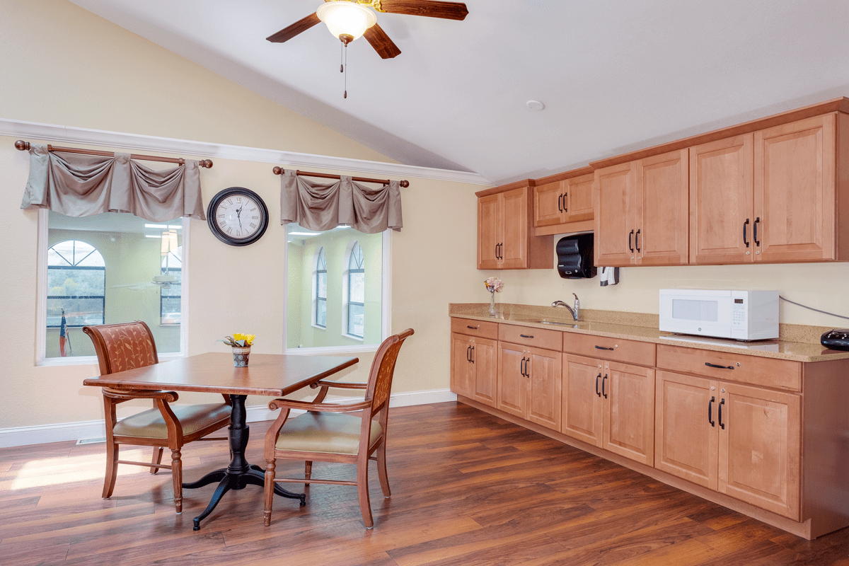 A cozy kitchen with wooden cabinets, a dining table set, and modern amenities.