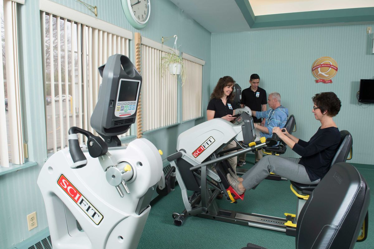 A group of people engaging in a physical therapy session using specialized exercise machines.